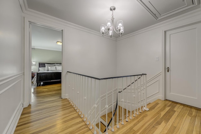 stairs with a decorative wall, a wainscoted wall, wood-type flooring, and ornamental molding