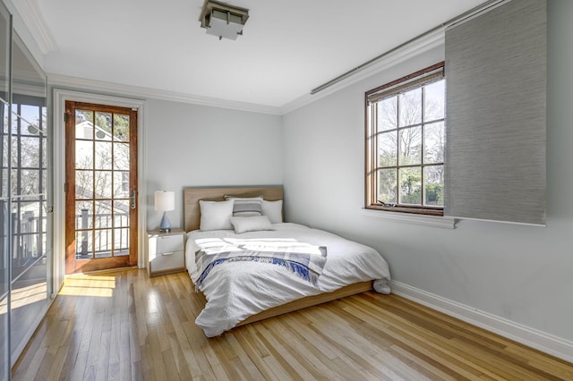 bedroom featuring hardwood / wood-style floors, crown molding, and multiple windows