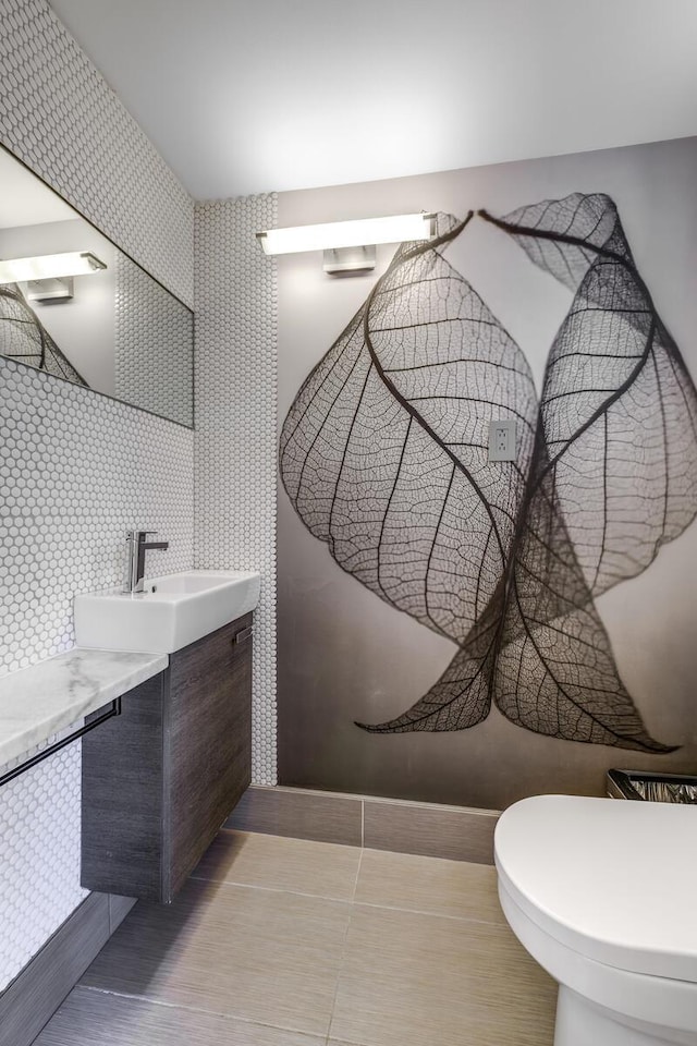 half bathroom with toilet, vanity, and tile patterned flooring