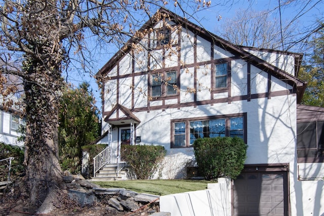 tudor home with a garage and stucco siding