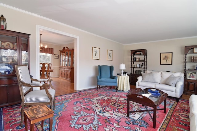 living room featuring a notable chandelier, crown molding, baseboards, and wood finished floors