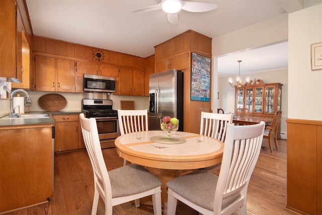 dining room with ceiling fan with notable chandelier and light wood-type flooring