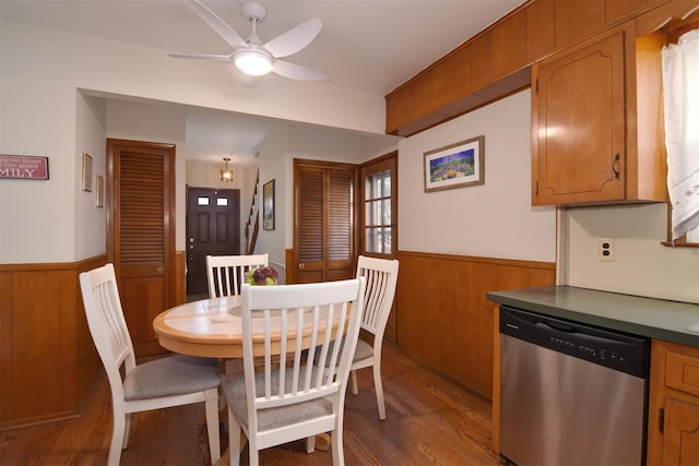 dining area with wainscoting, wood walls, and ceiling fan