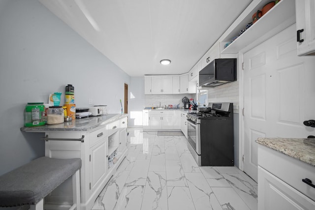 kitchen with light stone countertops, stainless steel range with gas stovetop, white cabinets, marble finish floor, and tasteful backsplash