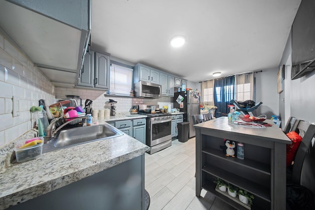 kitchen featuring a sink, light countertops, decorative backsplash, appliances with stainless steel finishes, and open shelves