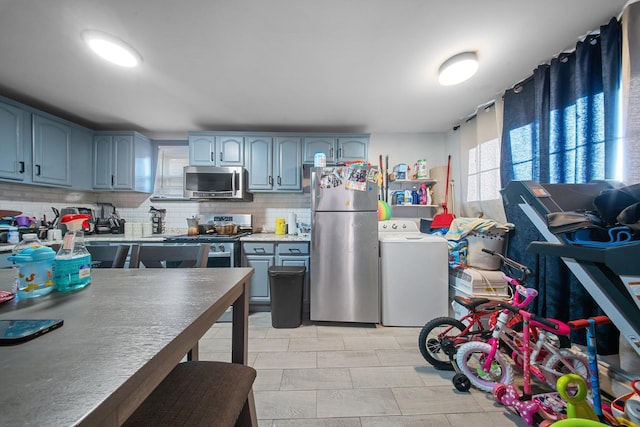 kitchen featuring blue cabinets, appliances with stainless steel finishes, light countertops, decorative backsplash, and washer / dryer