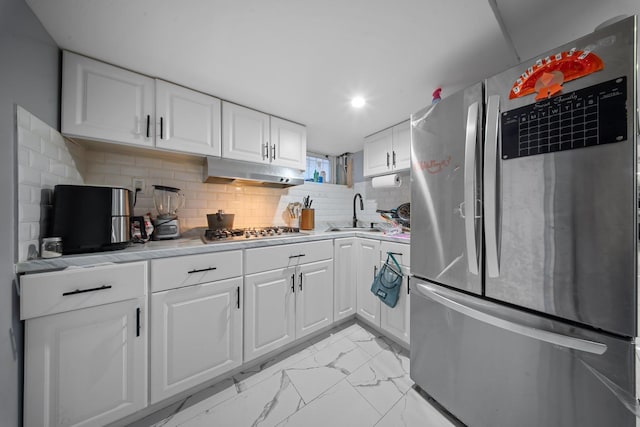 kitchen with marble finish floor, under cabinet range hood, a sink, appliances with stainless steel finishes, and light countertops