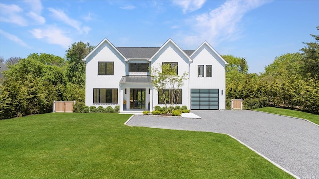 modern farmhouse style home featuring a front yard, a standing seam roof, gravel driveway, an attached garage, and metal roof