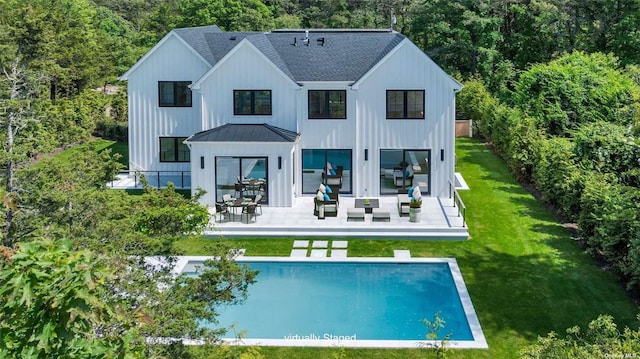 rear view of house featuring a shingled roof, a yard, a patio area, an outdoor pool, and a standing seam roof