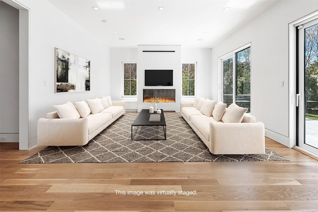 living room with a glass covered fireplace, recessed lighting, and wood finished floors