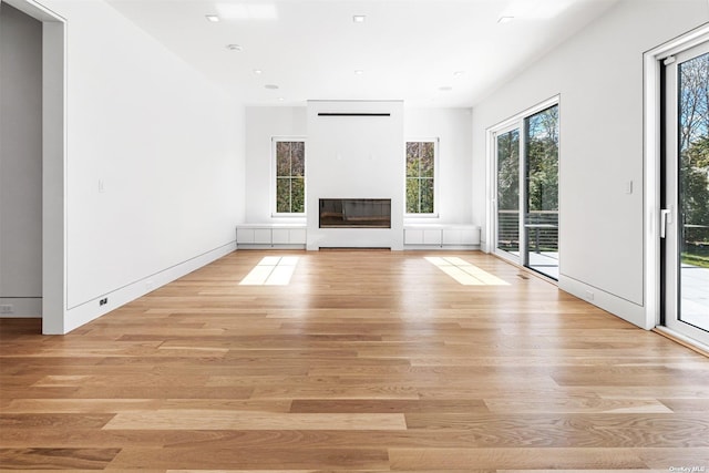 unfurnished living room featuring a glass covered fireplace, recessed lighting, and light wood-type flooring