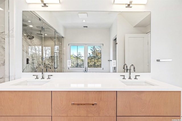 bathroom featuring a sink, a marble finish shower, and double vanity