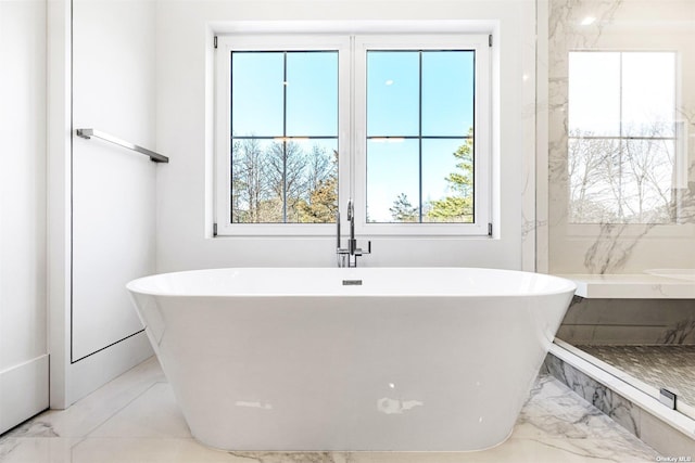 full bathroom with a freestanding bath and marble finish floor