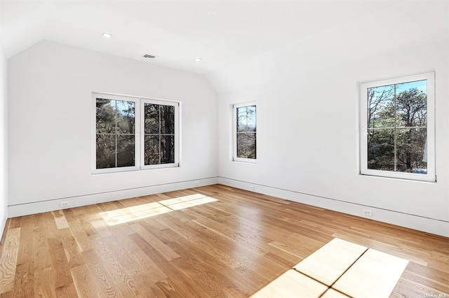 unfurnished room featuring visible vents, lofted ceiling, and wood finished floors