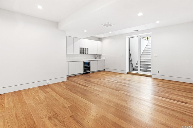 interior space with stairway, beverage cooler, baseboards, light wood-style flooring, and recessed lighting