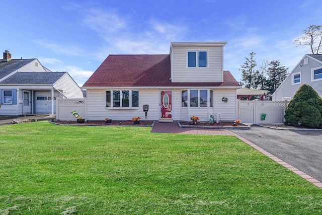 view of front of home with aphalt driveway, roof with shingles, a front lawn, and fence