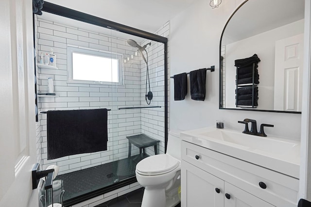 bathroom with tile patterned flooring, toilet, vanity, and a tile shower