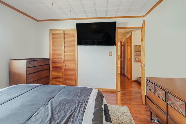 bedroom featuring a closet, ornamental molding, baseboards, and wood finished floors