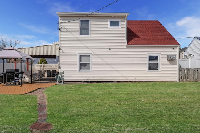 rear view of house with a gazebo, a wooden deck, a lawn, and fence