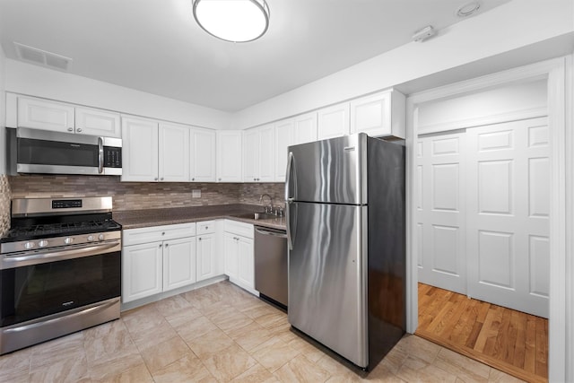 kitchen with white cabinets, visible vents, backsplash, and stainless steel appliances