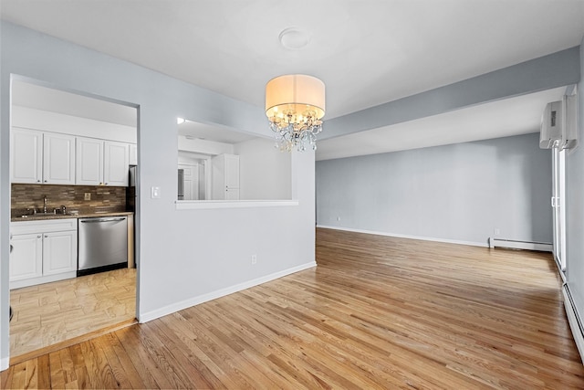 unfurnished dining area featuring baseboards, a sink, light wood-type flooring, baseboard heating, and a chandelier