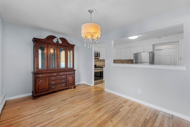 dining space featuring light wood-type flooring, baseboards, a notable chandelier, and a baseboard heating unit