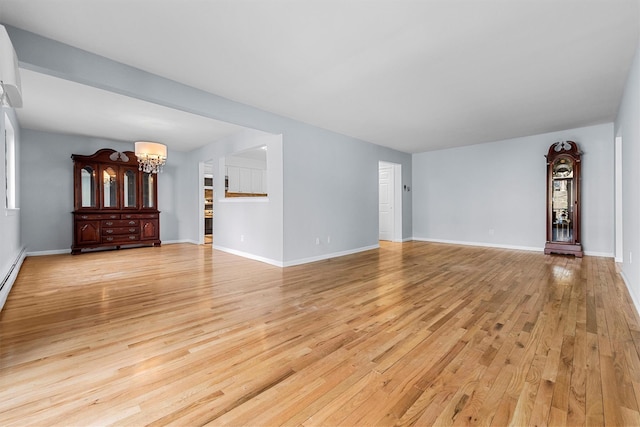 unfurnished living room with light wood-style flooring, baseboards, and a chandelier