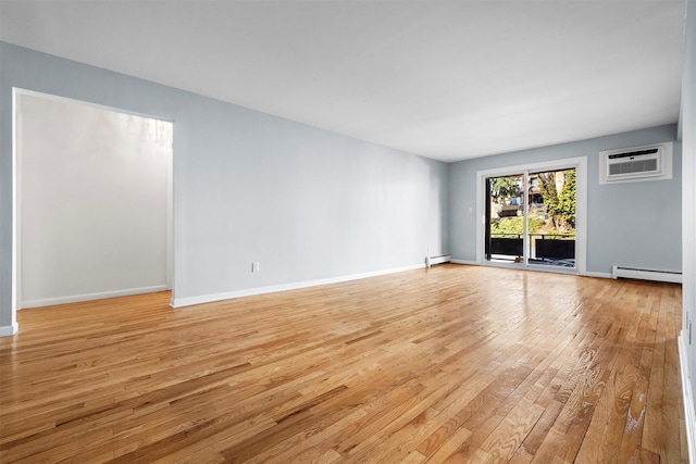 spare room featuring a wall mounted air conditioner, a baseboard radiator, baseboards, and light wood-style floors