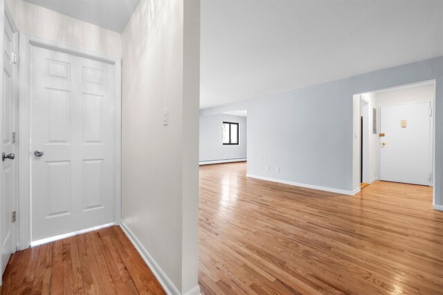 corridor with baseboards, light wood-style floors, and a baseboard radiator