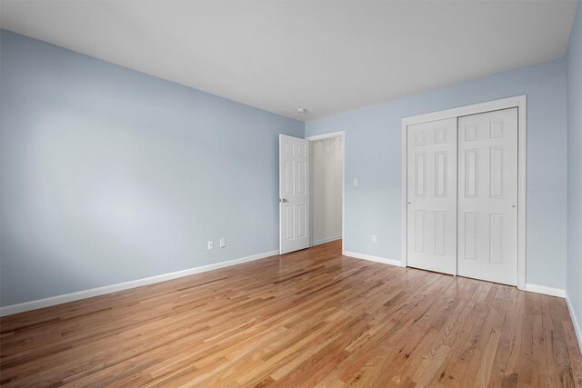 unfurnished bedroom with a closet, light wood-type flooring, and baseboards