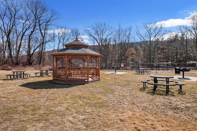 view of property's community with a gazebo, a yard, a forest view, and fence