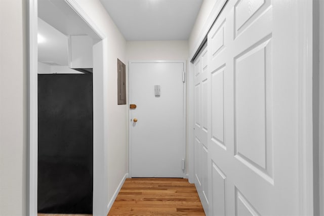 hallway featuring electric panel and light wood-style flooring