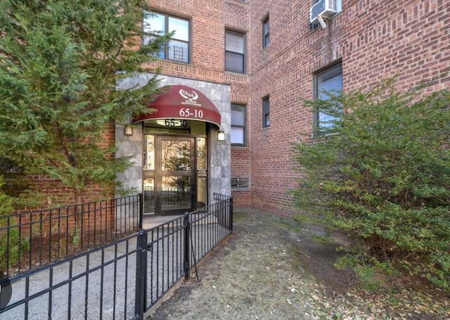 view of exterior entry with cooling unit and brick siding