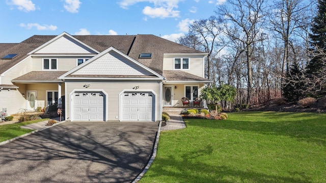 view of front of property featuring a front yard, roof with shingles, an attached garage, covered porch, and aphalt driveway