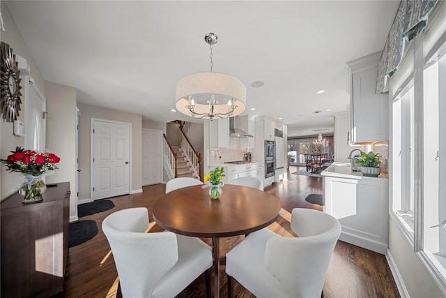 dining room with dark wood-type flooring, an inviting chandelier, and stairs