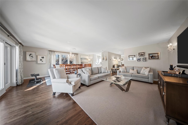 living room featuring an inviting chandelier, dark wood-style floors, and baseboards