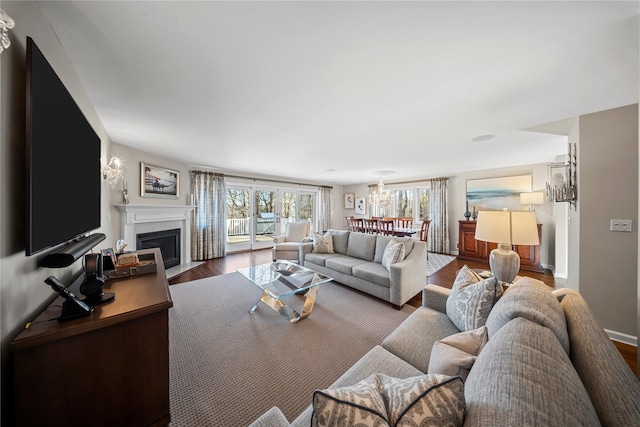 living area with baseboards, a fireplace with flush hearth, and wood finished floors