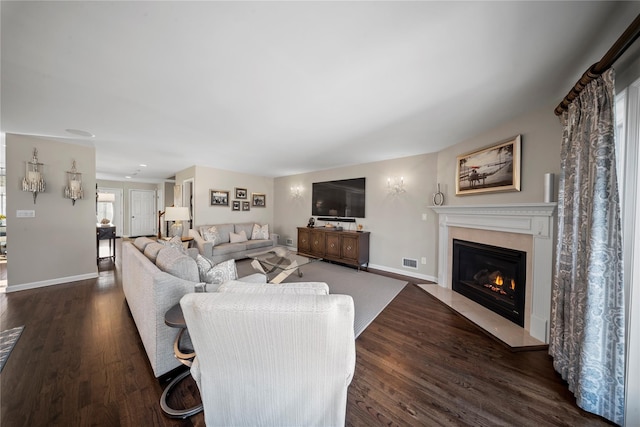 living room with a fireplace, visible vents, wood finished floors, and baseboards