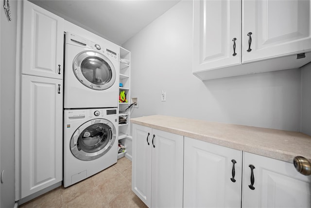 laundry room featuring light tile patterned floors, cabinet space, and stacked washing maching and dryer