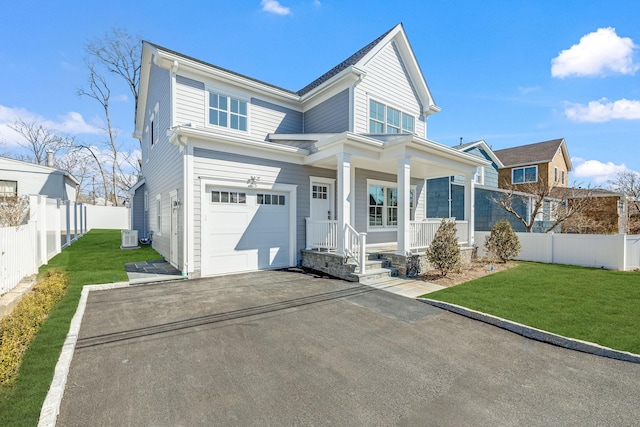 view of front of home with an attached garage, covered porch, a front yard, and fence