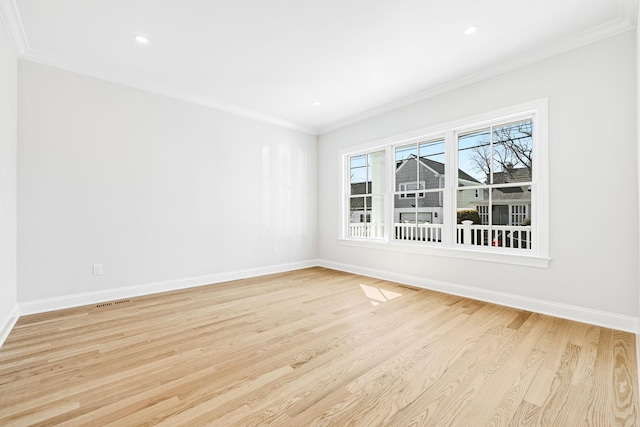 empty room featuring light wood-type flooring, crown molding, and baseboards