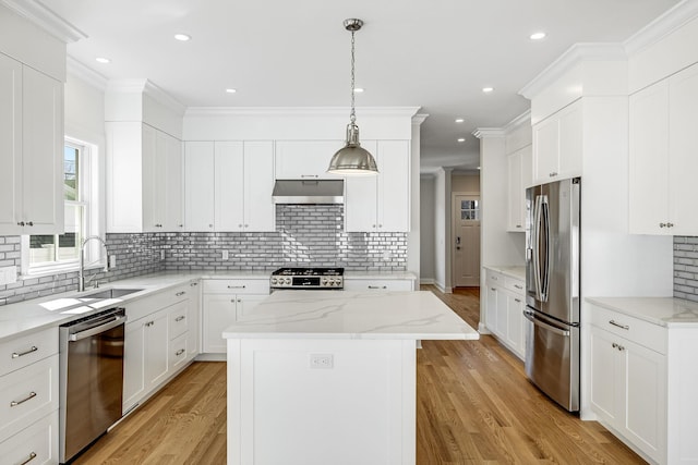 kitchen with light wood finished floors, a kitchen island, stainless steel appliances, under cabinet range hood, and crown molding