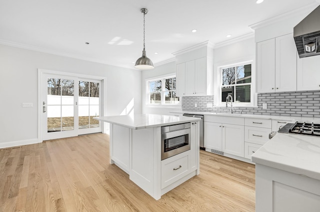 kitchen with backsplash, ornamental molding, appliances with stainless steel finishes, and a sink