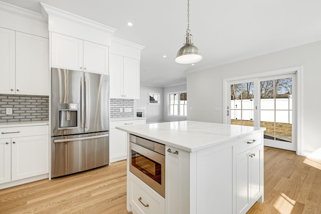 kitchen with light wood finished floors, ornamental molding, appliances with stainless steel finishes, decorative light fixtures, and backsplash