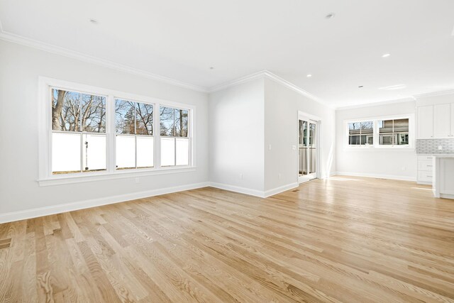 unfurnished living room with light wood-style flooring, crown molding, and baseboards