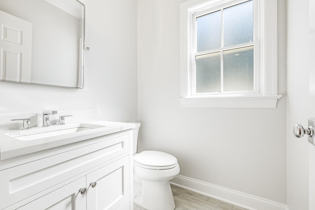 bathroom with a wealth of natural light, toilet, vanity, and baseboards