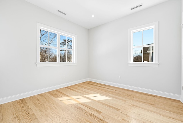 spare room featuring visible vents, light wood-type flooring, and baseboards