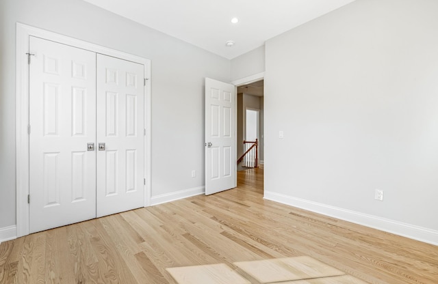 unfurnished bedroom featuring a closet, recessed lighting, baseboards, and light wood finished floors