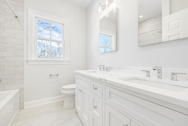 full bath with a sink, baseboards, toilet, and double vanity