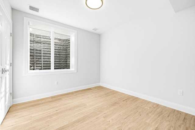 spare room featuring light wood-style flooring, baseboards, and visible vents